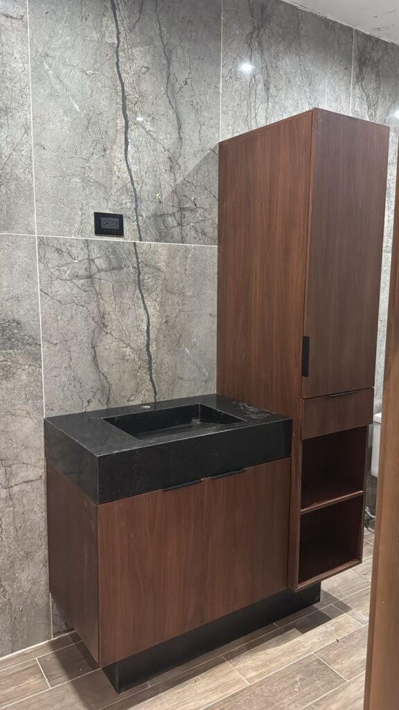 Mueble de baño de nogal con lavabo de piedra negra y torre de guardado